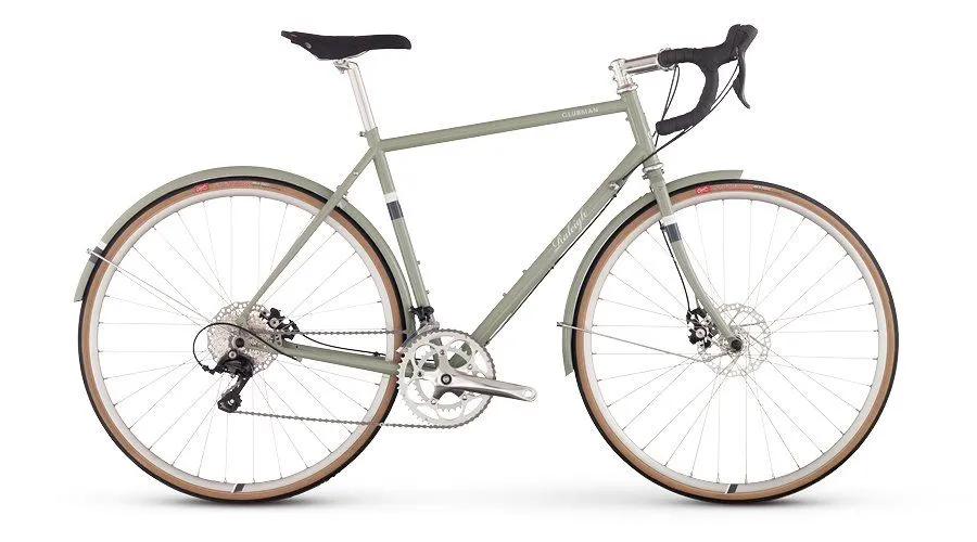 A sage green touring bike with fenders and drop handlebars